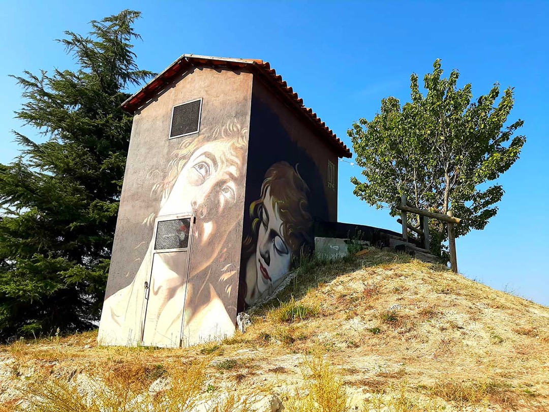 Murale di un volto sulla cabina di una collina di Camo, Museo a Cielo Aperto